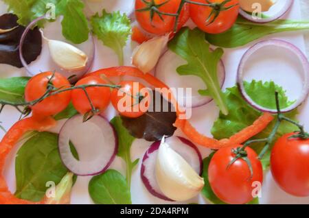 Bunte Salat Zutaten Muster aus Tomaten, Ruccola, lila Zwiebelringe, rote Paprika, Chili, Knoblauch, Gurkenscheiben und Basilikum auf weiß Stockfoto