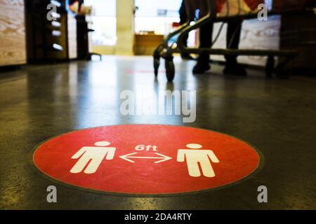 Roter Kreis Symbol Schild gedruckt auf dem Boden in US-Supermarkt Kassenqueue informiert die Leute, 6 Fuß Abstand zu halten Voneinander zu verhindern, Ausbreitung Stockfoto