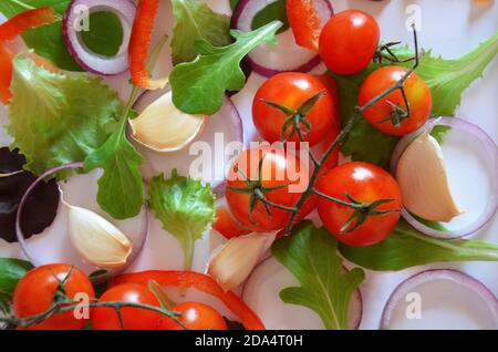 Bunte Salat Zutaten Muster aus Tomaten, Ruccola, lila Zwiebelringe, rote Paprika, Chili, Knoblauch, Gurkenscheiben und Basilikum auf weiß Stockfoto