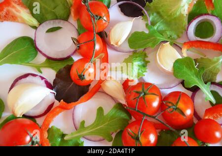 Bunte Salat Zutaten Muster aus Tomaten, Ruccola, lila Zwiebelringe, rote Paprika, Chili, Knoblauch, Gurkenscheiben und Basilikum auf weiß Stockfoto