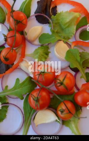 Bunte Salat Zutaten Muster aus Tomaten, Ruccola, lila Zwiebelringe, rote Paprika, Chili, Knoblauch, Gurkenscheiben und Basilikum auf weiß Stockfoto