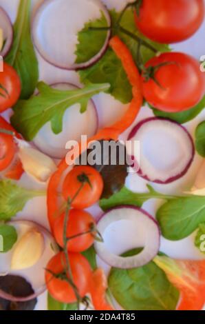 Bunte Salat Zutaten Muster aus Tomaten, Ruccola, lila Zwiebelringe, rote Paprika, Chili, Knoblauch, Gurkenscheiben und Basilikum auf weiß Stockfoto