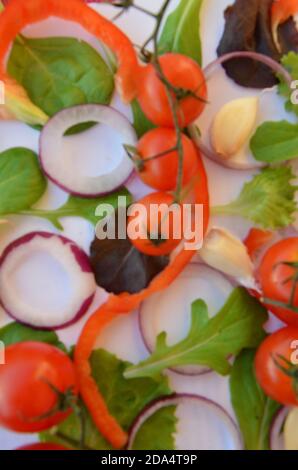 Bunte Salat Zutaten Muster aus Tomaten, Ruccola, lila Zwiebelringe, rote Paprika, Chili, Knoblauch, Gurkenscheiben und Basilikum auf weiß Stockfoto