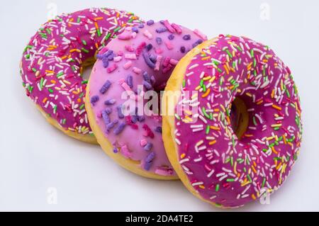 Drei Beerendonut, rosa Donut, drei, drei Donut in einem rosa Glasett, Erdbeer- und Himbeer-Donuts, Walnussdonut auf weißem Grund Stockfoto