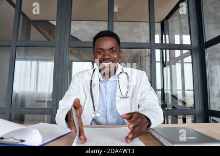 Afrikanischer männlicher Arzt im Gespräch mit der Kamera während telemedizinische mobile Beratung. Stockfoto