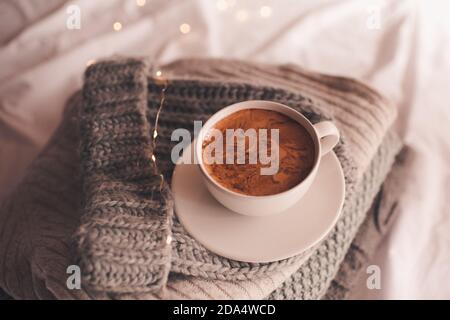 Tasse Kaffee auf gestrickten Stoffen im Bett aus nächster Nähe. Winterurlaub Saison. Guten Morgen. Stockfoto