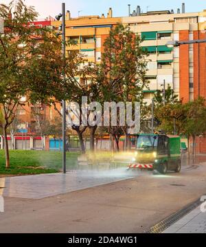 Bewässerungsmaschine Reinigung Straße von thе kleiner Park in Wohngebiet mit Wohnblöcken moderner Architektur, Barcelona, Spanien Stockfoto