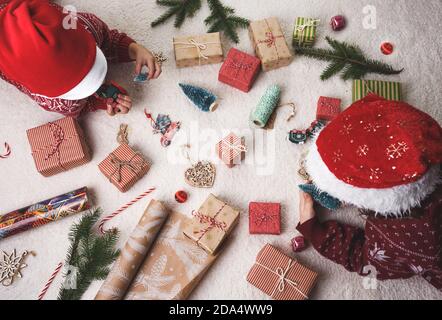 Zwei Kinder zu Hause auf dem Teppich legen Weihnachtsgeschenke aus. Stockfoto