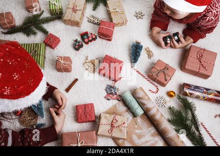 Zwei Kinder zu Hause auf dem Teppich legen Weihnachtsgeschenke aus. Stockfoto