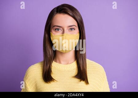 Foto von jungen hübschen Brünette Mädchen tragen Gesichtsmaske lässig Gestrickter gelber Pullover isoliert Farbe lila Hintergrund Stockfoto