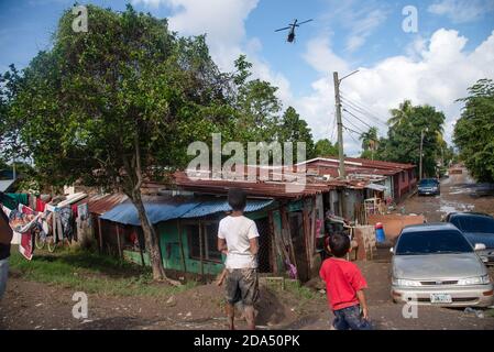 Ein Rettungshubschrauber, der über einer überschwemmten Gemeinde von La Lima, Honduras, fliegt. Ein provisorisch behelfsmäßiges Flüchtlingslager hat die mittlere und eine Spur der Hauptautobahn in San Pedro Sula, Honduras, übernommen, wo die schlimmsten Überschwemmungen durch Hurrikan Eta fast 2 Millionen Menschen getroffen haben. Der honduranischen Regierung fehlen die Ressourcen und die Logistik, um die betroffenen Menschen zu beherbergen. Stockfoto