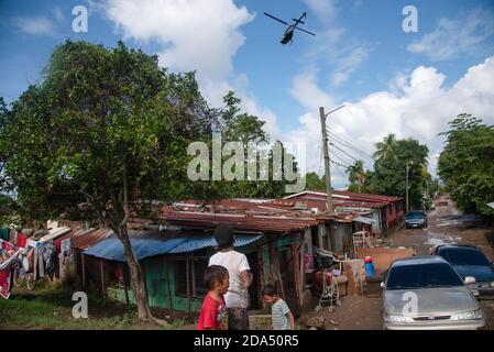 Ein Rettungshubschrauber, der über einer überschwemmten Gemeinde von La Lima, Honduras, fliegt. Ein provisorisch behelfsmäßiges Flüchtlingslager hat die mittlere und eine Spur der Hauptautobahn in San Pedro Sula, Honduras, übernommen, wo die schlimmsten Überschwemmungen durch Hurrikan Eta fast 2 Millionen Menschen getroffen haben. Der honduranischen Regierung fehlen die Ressourcen und die Logistik, um die betroffenen Menschen zu beherbergen. Stockfoto