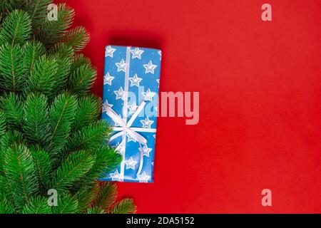 Nachbildung von Weihnachtsbaum, blaue Geschenkbox mit Sternen, Schneeflocken und weißem Band auf rotem Hintergrund, mit Platz für Text Stockfoto