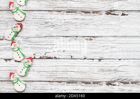 Weiß rustikalen Holz Hintergrund mit eisigen Weihnachten Schneemann Cookies oder Kekse mit Karotten Nase, santa Hut und Scraf mit Platz für Text . Schneemänner erschossen Stockfoto