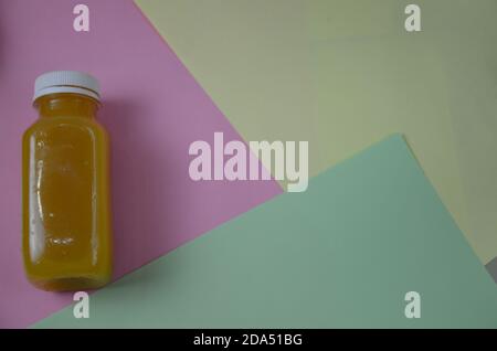 Flasche Orangensaft Schuss. Orange Bio frisch gepressten Saft in einer kleinen Plastikflasche auf einem bunten Hintergrund neben geschnittenen Orange und einer Minze Stockfoto