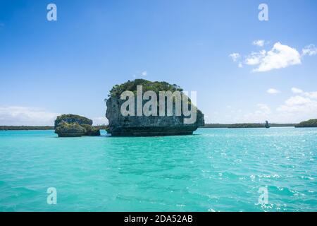 Wunderschöne Seeslandschaft der UPI Bay, Pines Island, neukaledonien: Türkisfarbene Lagune, typische Felsen, üppige Vegetation, blauer Himmel Stockfoto