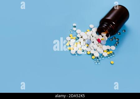 Medizinische Flasche und Medikationspillen verschüttet auf pastellblauen Hintergrund. Gesundheitswesen, Pharmazie, Medizin Konzept Stockfoto