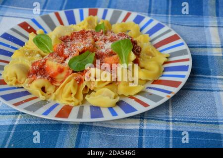 Hausgemachte Tortellini Pasta mit Tomatensauce, Kräutern und Knoblauch, Basilikum in, mit Parmesan-Käse gekrönt Stockfoto
