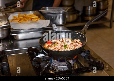 Garen Garnelen mit Austern mit Gemüse Tomaten und Grün und Mit Omelett auf einer Bratpfanne - auf einem Herd Mit Feuerhintergrund Stockfoto