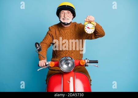 Porträt seiner er schön attraktiv fröhlich fröhlich zuversichtlich bärtig Grauhaarige Mann Reiten Moped hält in der Hand kindisch Uhr Pünktlichkeit Isoliert Stockfoto