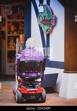 Rückansicht einer älteren Frau im Mobilitätsroller, die einen Body & Bath Shop in Gatlinburg, TN, USA betritt Stockfoto