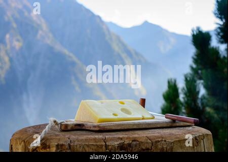 Käsesammlung, französischer emmental de savoie Käse mit runden Löchern, serviert im Freien in der Savoyer Region, mit Berggipfeln im Sommer auf dem Backgrou Stockfoto