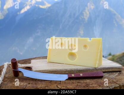 Käsesammlung, französischer emmental de savoie Käse mit runden Löchern, serviert im Freien in der Savoyer Region, mit Berggipfeln im Sommer auf dem Backgrou Stockfoto