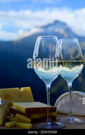 Schmackhafter Käse und Wein aus Savoyen in Frankreich, beaufort, abondance, emmental, Tomme und Reblochon de savoie Käse und ein Glas Weißwein serviert Stockfoto