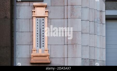 Ein riesiges, vergoldetes Quecksilberthermometer um 25 mit einer Skala von minus 54 bis plus 54 Grad um Null, an der Steinmauer auf der Straße an s gehängt Stockfoto