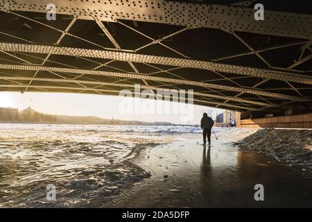 Silhouette des Skifahrers auf dem Eis der gefrorenen Neva Fluss unter der Palastbrücke im Winter bei Sonnenuntergang Stockfoto