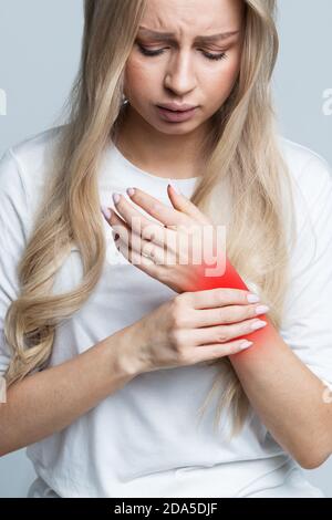 Junge kaukasische Frau, die ihr schmerzhaftes Handgelenk hält, verursacht durch längere Arbeit am Computer, Laptop. Karpaltunnelsyndrom, Arthritis, neurologische Erkrankung Stockfoto