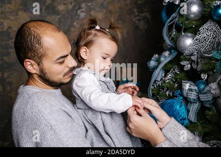 Glückliche Familie schmücken weihnachtsbaum zu Hause zusammen. Frohe Weihnachten und frohe Feiertage. Stockfoto