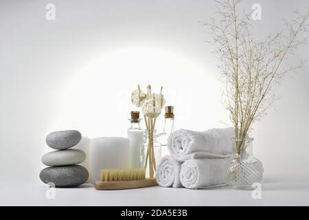 Komposition mit einer Kerze und Spa Steinen und einem natürlichen Pinsel für Körpermassage auf einem hellen Hintergrund. Das Konzept der Hautpflege. Badezubehör. Stockfoto