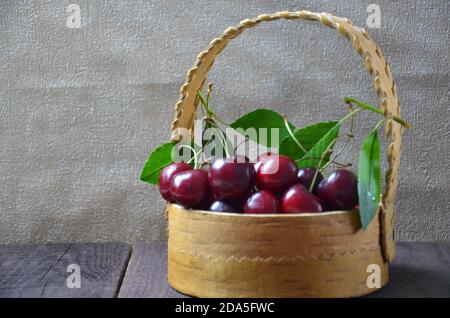 Ein kleiner Junge nimmt mit der linken Hand ein paar Kirschen von einem Bsket, Nahaufnahme Stockfoto
