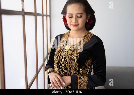 Ein Porträt einer traditionellen javanischen Frau. Stehen am Fenster Stockfoto