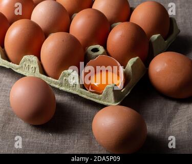 Eigelb in einer zerbrochenen Eierschale mit einem Karton Eier Stockfoto