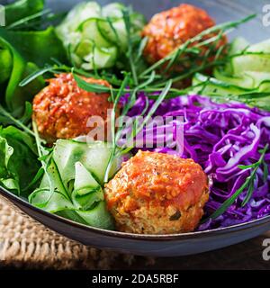 Keto/ketogene Lebensmittel. Hühnerfleischbällchen und Salat auf Holzhintergrund. Abendessen. Buddha-Schale. Stockfoto