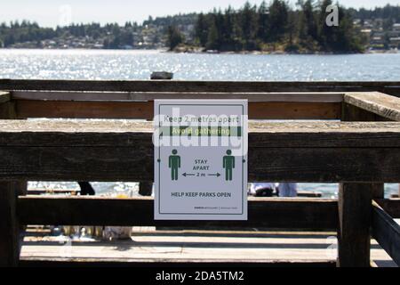 Vancouver, Kanada - 13. Juli 2020: Blick auf das Schild "Halten Sie 2 Meter auseinander, vermeiden Sie sammeln" auf einem Pier im Belcarra Regional Park Stockfoto