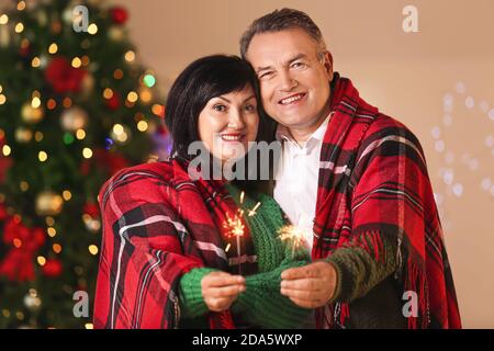 Reifes Paar mit Wunderkerzen Weihnachten zu Hause feiern Stockfoto