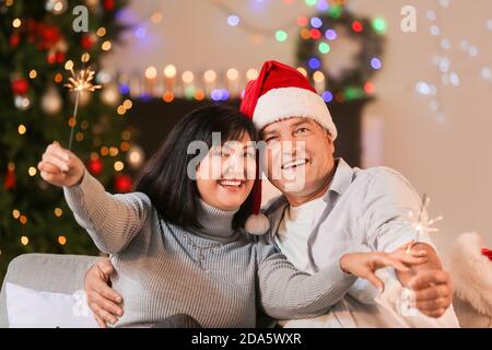 Reifes Paar mit Wunderkerzen Weihnachten zu Hause feiern Stockfoto