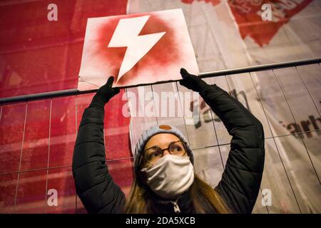 Ein Protestler mit Gesichtsmaske hält ein Plakat mit dem Symbol des Frauenwiderstands, dem roten Blitz während der Demonstration.die Gegner des Urteils des Verfassungsgerichts über Abtreibung protestierten erneut. Hunderte von Menschen versammelten sich vor dem Ministerium für Bildung, um den Rücktritt des Ministers für Bildung und Wissenschaft, Przemyslaw Czarnek, zu fordern, der für seine homophoben und chauvinistischen öffentlichen Äußerungen bekannt ist. Bei mehreren Gelegenheiten zerstreute die Polizei gewaltsam Demonstranten, die versucht hatten, den Verkehr zu blockieren und unerwartet durch das Stadtzentrum marschierten. Zahlreich Stockfoto