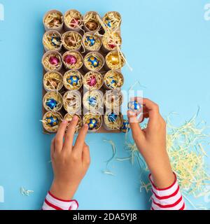 Toilettenrolle Adventskalender Handwerk, DIY, Schritt 3, Füllen mit Süßigkeiten, Draufsicht, blauer Hintergrund, Aktivität für Kinder Tutorial Stockfoto