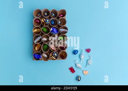 Gebrauchte Toilettenpapierrolle Adventskalender Handwerk, DIY, Schritt 3, Füllen mit Süßigkeiten, Draufsicht, blauer Hintergrund, Aktivität für Kinder Tutorial Stockfoto