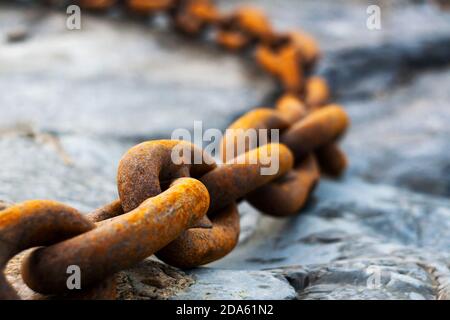 Große rostige alte Kette auf nassen Steinen Stockfoto