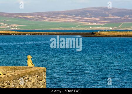 Teddybär aus Stein sitzt auf Felsen und beobachtet das blaue Meer Und Hügel Stockfoto