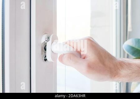 Die Hand öffnet ein Kunststofffenster, der Mechanismus bricht. Stockfoto