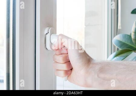 Die Hand öffnet ein Kunststofffenster, der Mechanismus bricht. Stockfoto