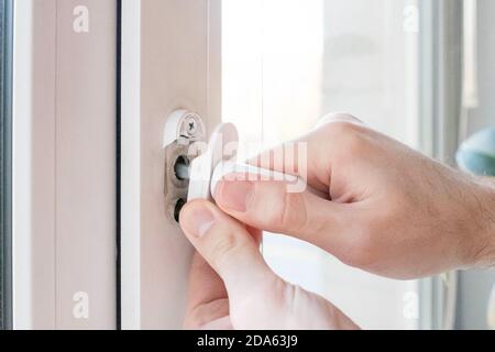 Riss im Fenstergriff. Der Mensch versucht zu reparieren. Stockfoto