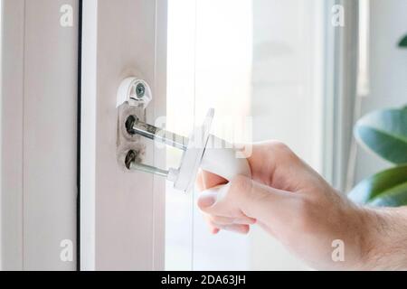 Der Fenstergriff hat Risse bekommen. Der Mann hält es in der Hand, die eisernen Stifte sind sichtbar. Stockfoto