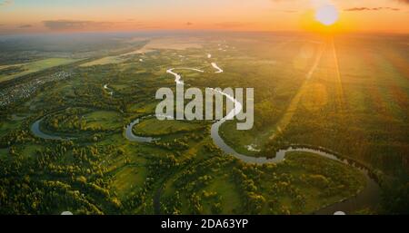 Luftaufnahme. Schöner Sonnenuntergang Sonne Sonnenschein Über Green Forest, Wiese Und Flusslandschaft In Sonnigen Abend. Von Oben Blick Auf Die Europäische Natur Aus Der Höhe Stockfoto